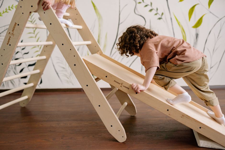 Children enjoying a wooden climbing slide indoors. Fun and active playtime.