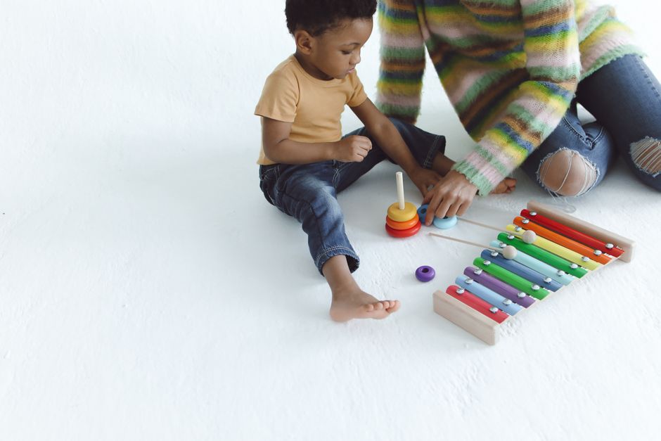 A mother and child enjoying playtime with a colorful xylophone on a white background.