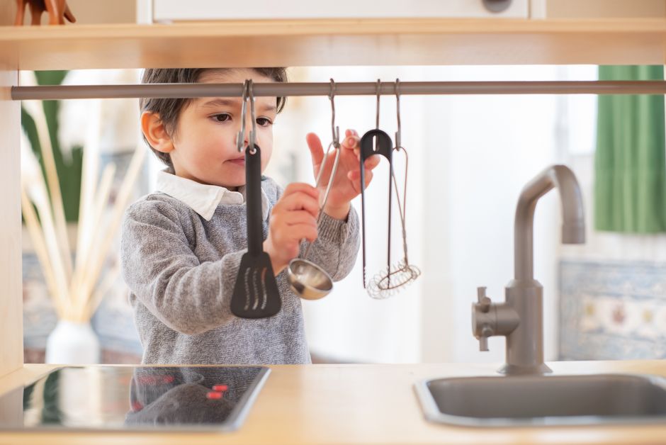 A young child having fun exploring kitchen utensils in a cozy indoor setting.