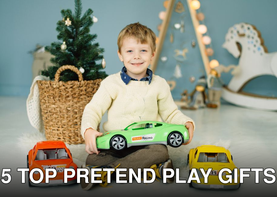 Smiling boy sitting on floor with bright toy cars and Christmas decorations, enjoying playtime indoors.