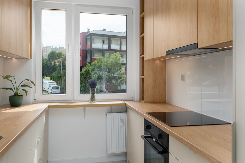 Sleek kitchen interior with wooden cabinets and outdoor view in Kraków.