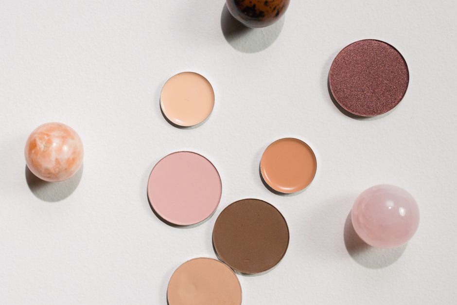 A stylish flat lay arrangement of various eyeshadow pans and decorative spheres on a clean white background, ideal for beauty and fashion visuals.