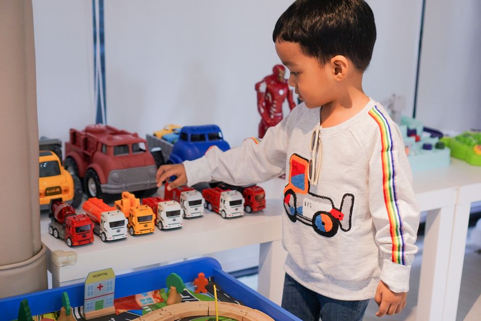 A young boy playing indoors with colorful toy trucks on a table, focused and imaginative.