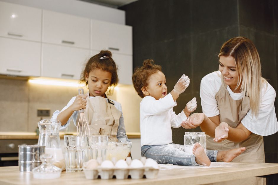 Mother and daughters baking together in the kitchen, filled with joy and flour