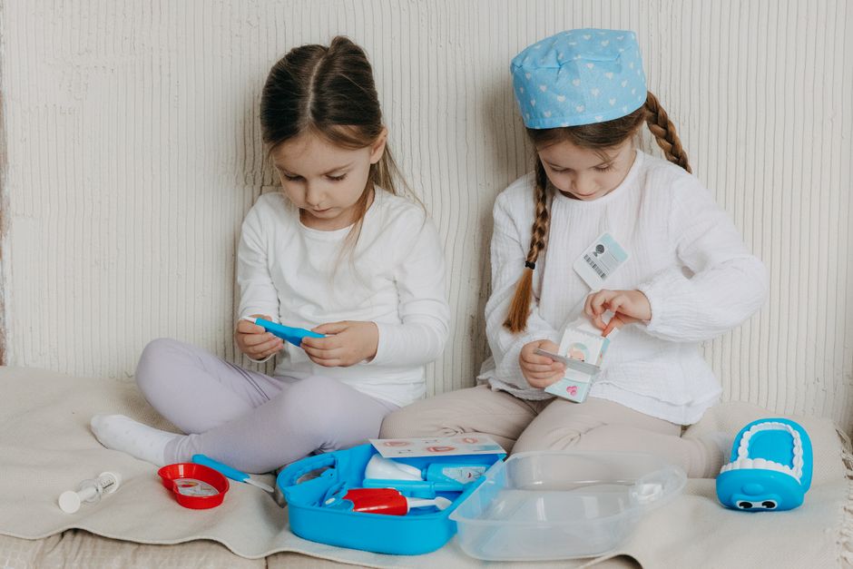 Two young girls playing with doctor toys indoors, exploring healthcare concepts through imaginative play.