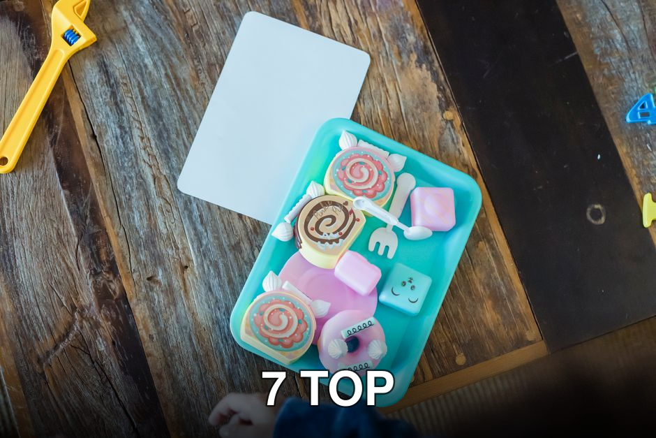 Top view of blue container with different colorful plastic toys of biscuits placed on wooden table