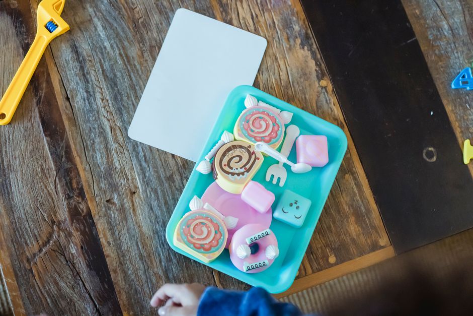 Top view of blue container with different colorful plastic toys of biscuits placed on wooden table