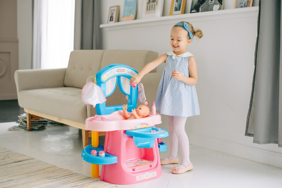 A young girl enjoys playing with her doll set in a cozy indoor living space.