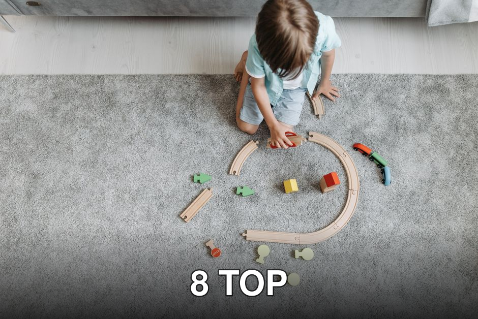 A child playing with a colorful toy train set on a living room carpet.