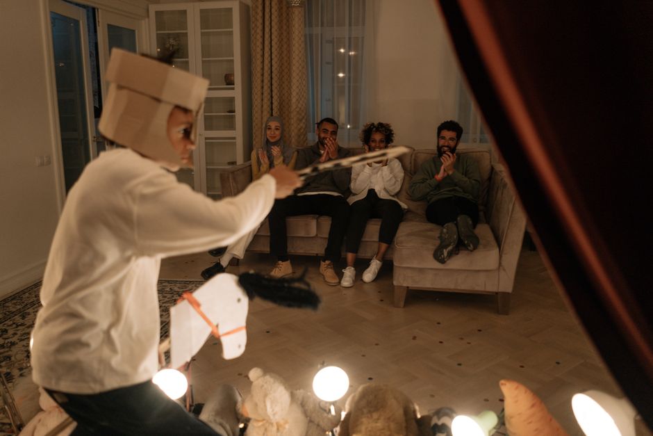 A child puts on a home performance with imaginative play, delighting family members watching on the couch.