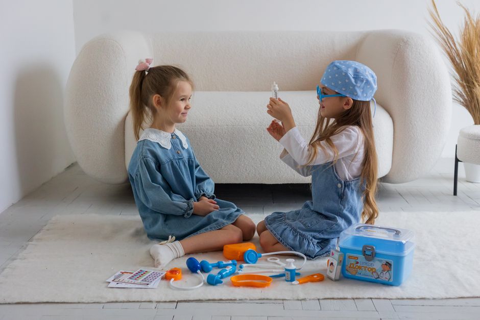 Two young girls playing doctor indoors with a toy medical kit. Creative pretend play activity.
