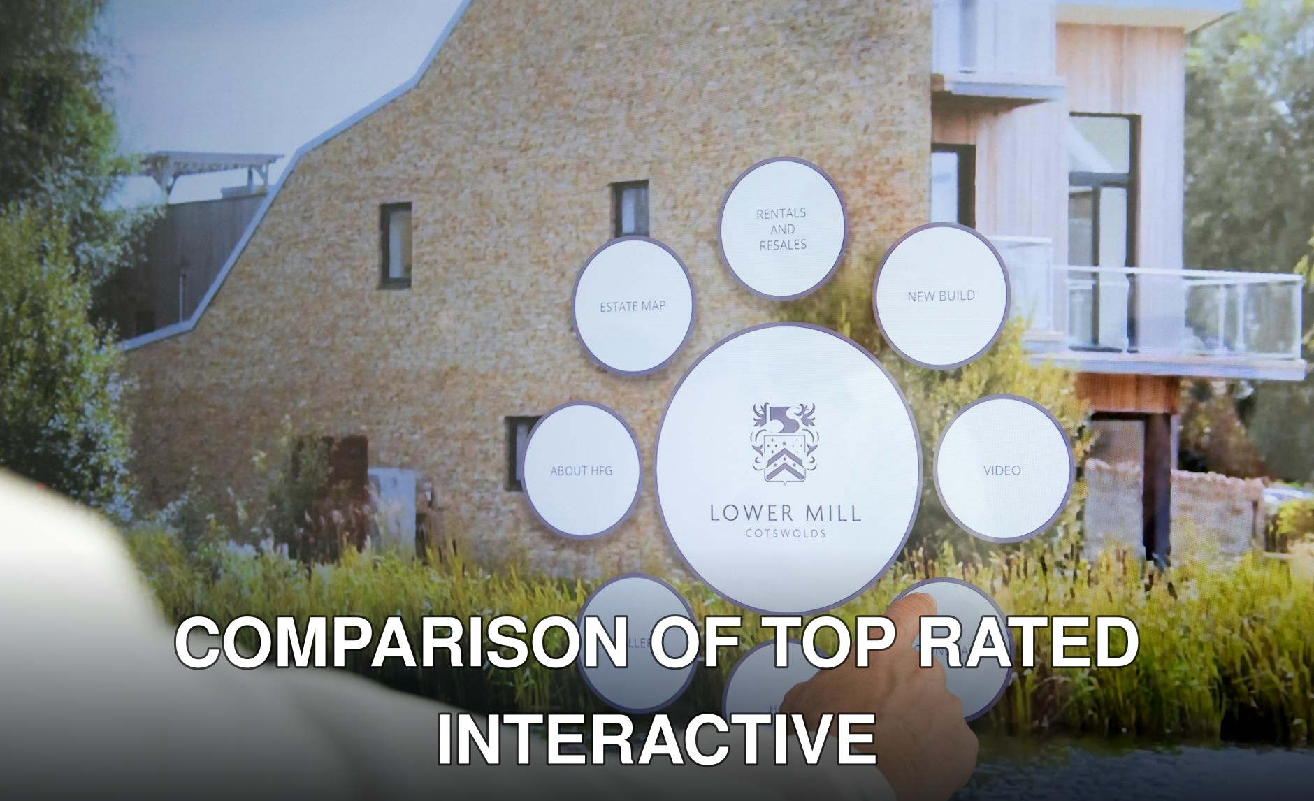 Close-up of a hand interacting with a real estate touchscreen display featuring Lower Mill Cotswolds.