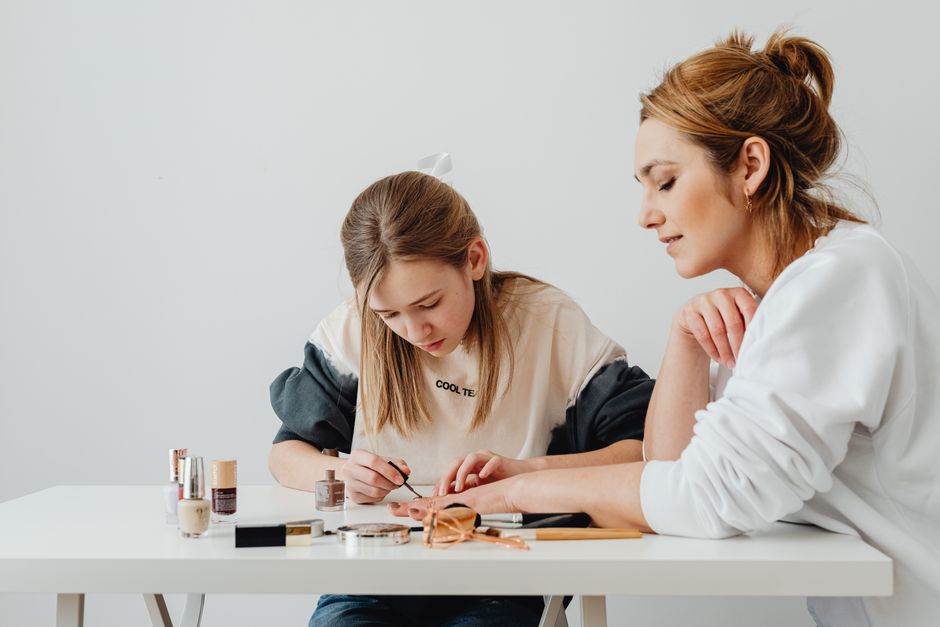 Mother and daughter enjoying a creative bonding session indoors with makeup.