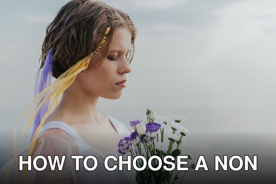 A serene woman with braided hair holds a colorful bouquet by the sea in soft light.