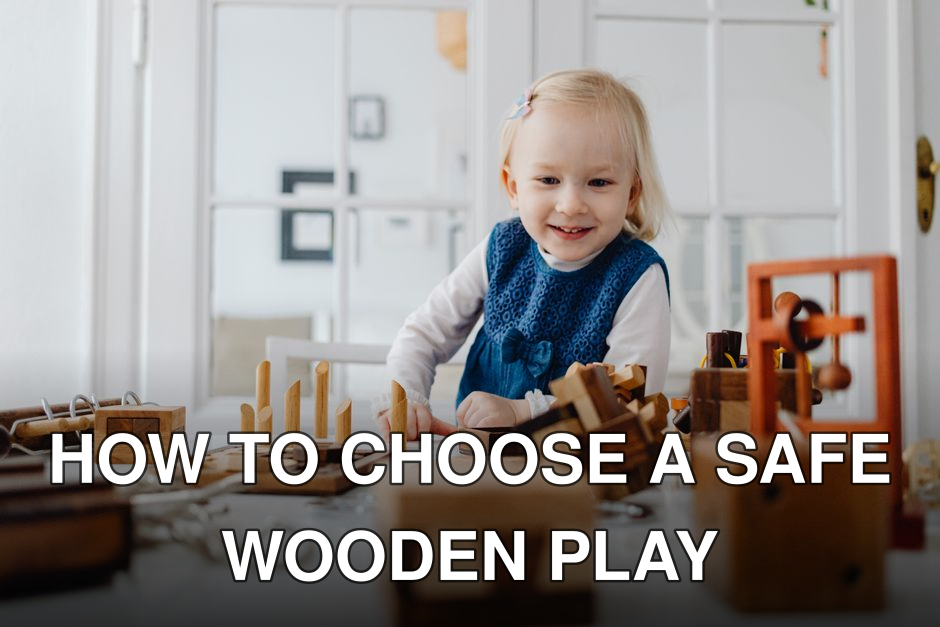 A happy toddler in a blue dress plays with wooden toys on a table indoors, enjoying a playful moment.