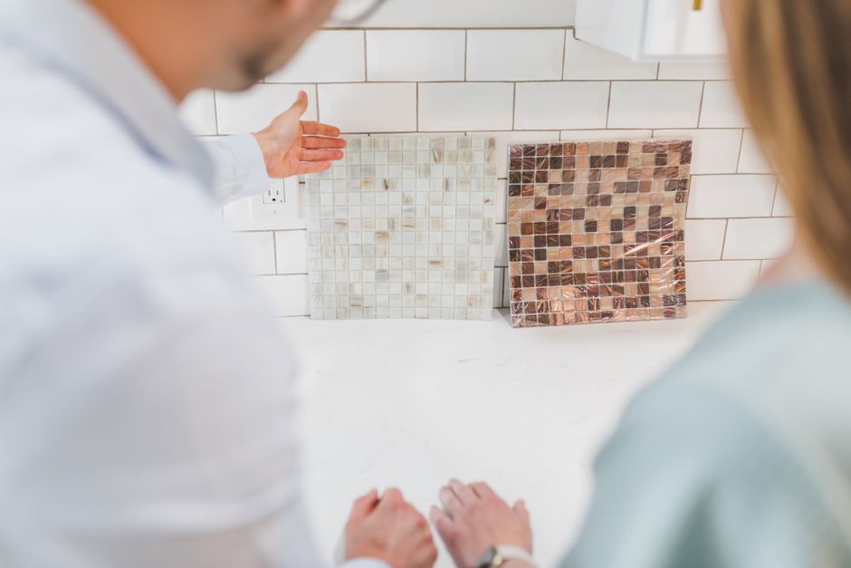 A couple examines decorative mosaic tiles for interior design in a contemporary kitchen setting.