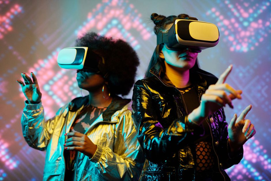 Two young women immersed in a futuristic virtual reality experience, showcasing vibrant technology.