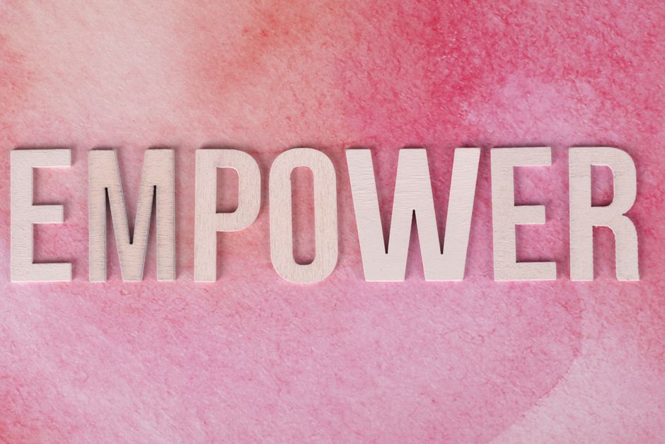 Wooden letters spelling 'EMPOWER' on a pink watercolor background.