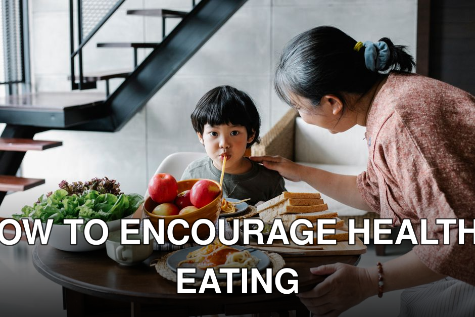 Cute funny Asian boy sucking spaghetti while gathering at dining table with positive grandmother in light kitchen
