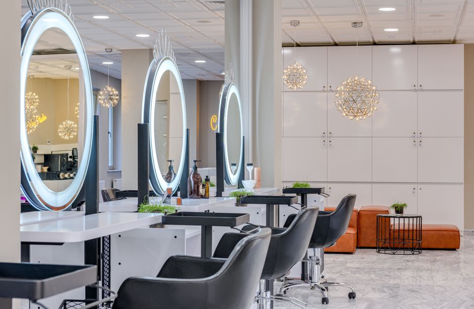 Bright and elegant hair salon interior featuring modern lighting and round mirrors for a chic and relaxing atmosphere.