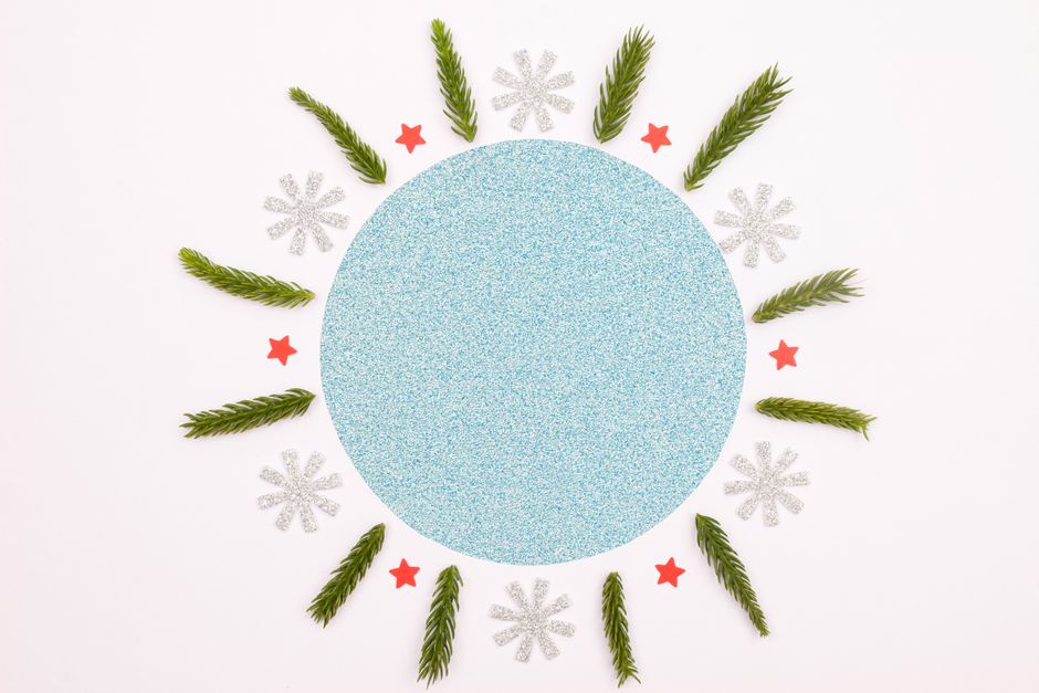 A circular holiday design with glitter paper, pine branches, stars, and snowflakes.