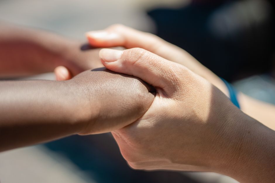 Close-up of diverse hands holding, symbolizing unity and compassion.