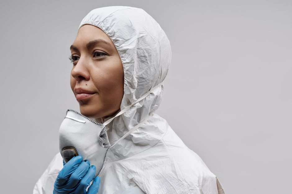 Woman wearing a protective suit and mask, emphasizing hygiene and safety during a pandemic.
