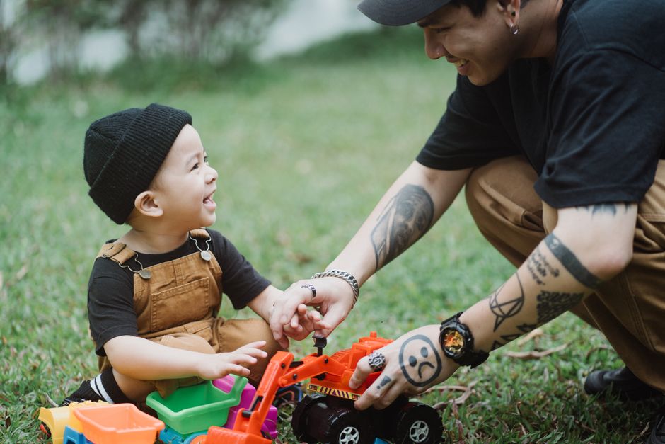 A joyful moment of a father and son playing with toys on the grass, capturing the essence of happy childhood.