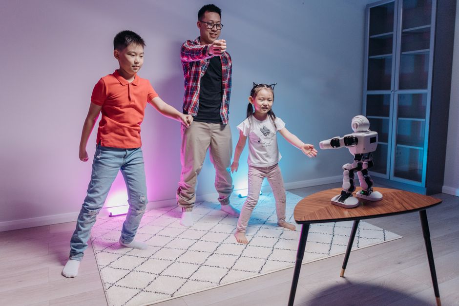 Family bonding with a robot in a living room, kids and adult in playful interaction.