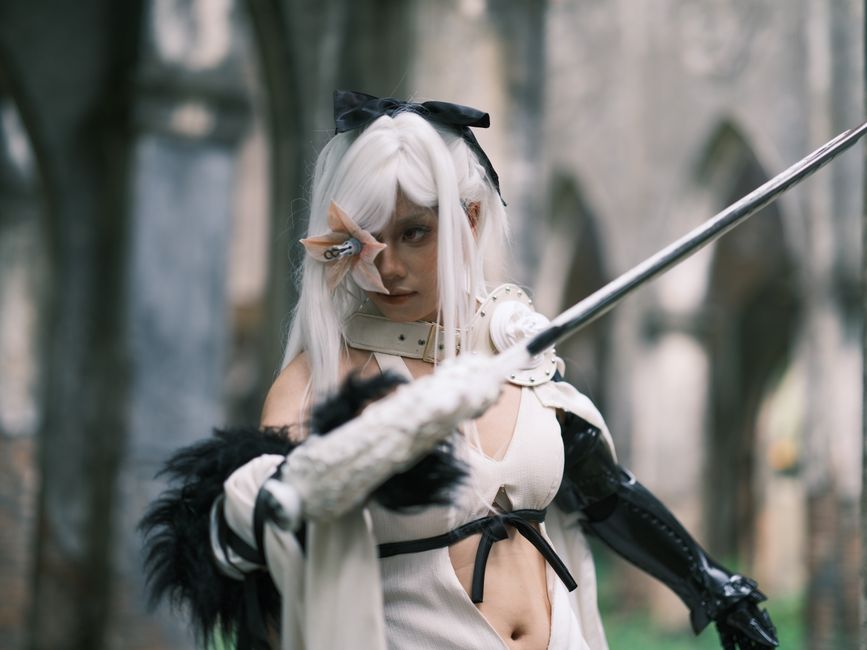 A striking image of a cosplayer in gothic attire wielding a sword in a historical setting in Vietnam.