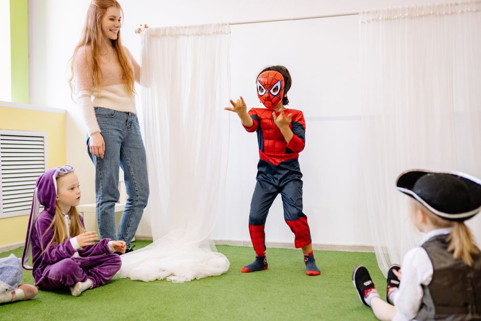 Children dressed up as superheroes playing in a joyful preschool setting indoors, promoting creativity and fun.
