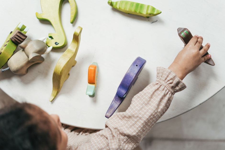 Child playing with colorful wooden toys in a playful indoor setting.
