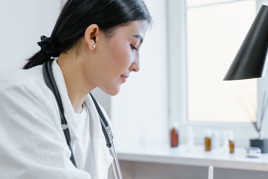 Close-up of an Asian female doctor working in an office setting, with medical tools visible.