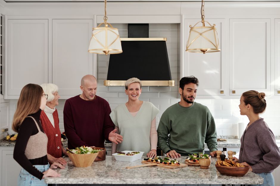 A multi-generational family enjoying a meal preparation together in a bright kitchen.