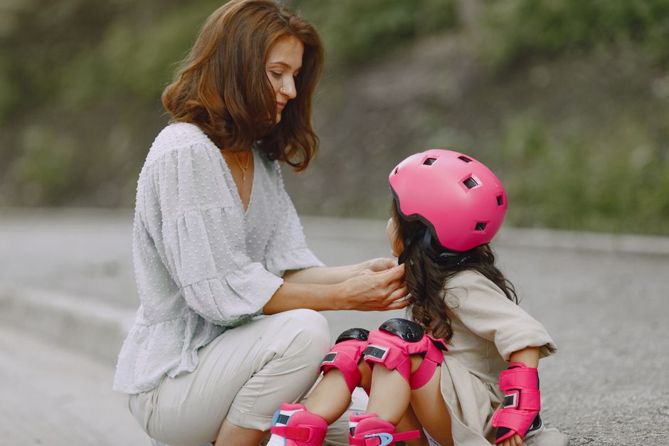 A caring mother assists her daughter with rollerblades and helmet, showcasing family bonding.