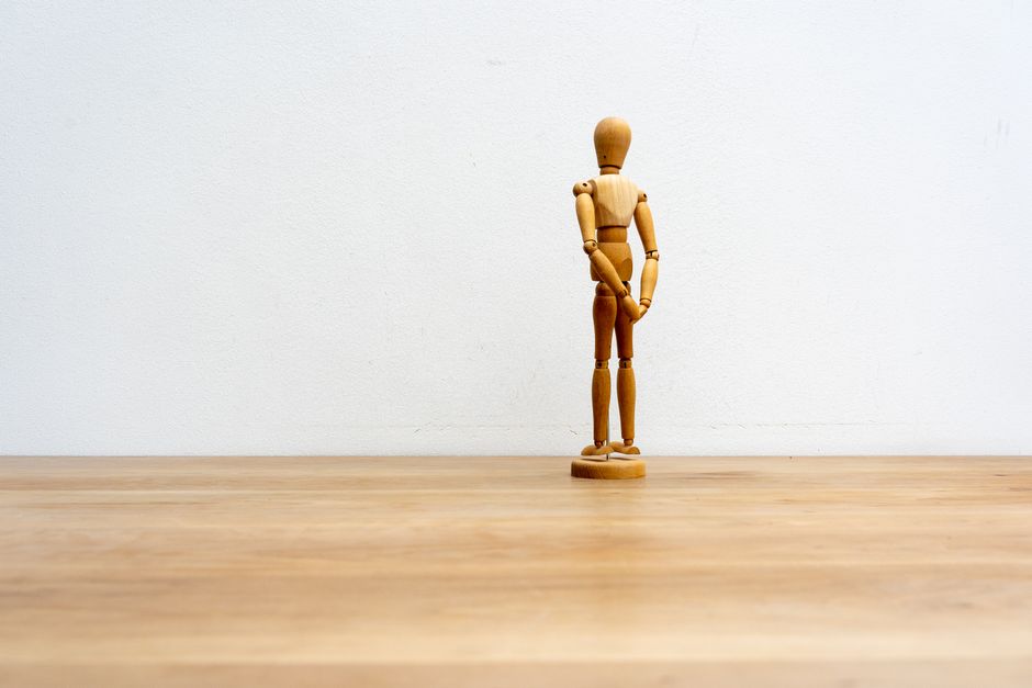 A wooden art mannequin on a wooden surface against a simple white backdrop.