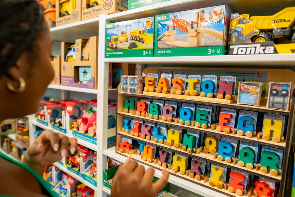 Woman explores colorful educational toys and alphabet blocks in a bustling toy store.