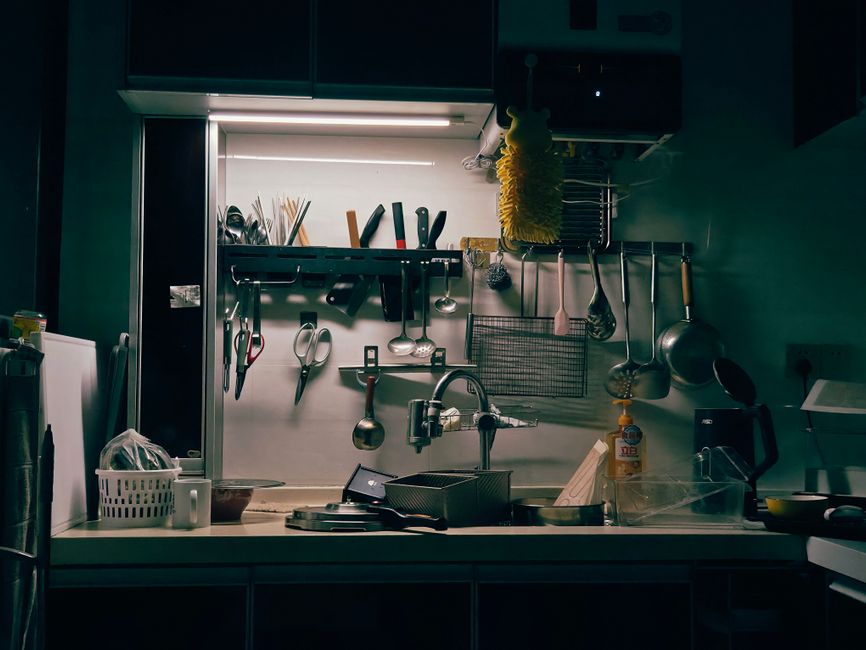 Well-organized kitchen with a variety of hanging utensils and kitchenware around a sink.