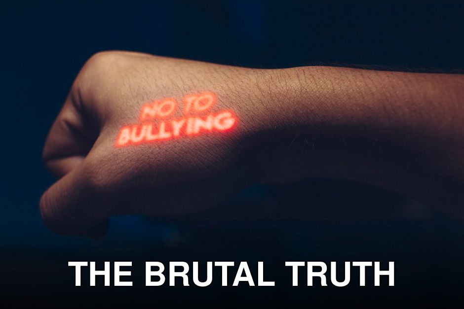 Close-up of a hand with a projected anti-bullying message in a dark setting.