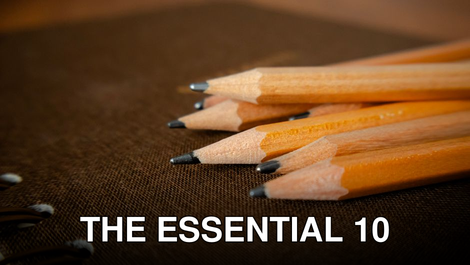 A detailed shot of sharpened pencils placed on a brown notebook surface.