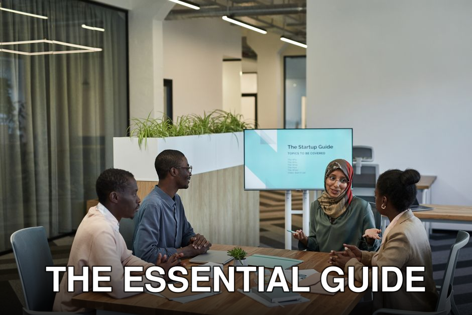 A diverse team discussing a startup guide in a modern office space, focusing on collaboration.