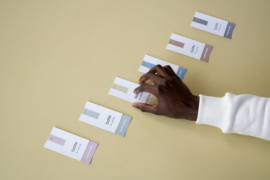 A person arranging color swatch tags on a smooth yellow surface.