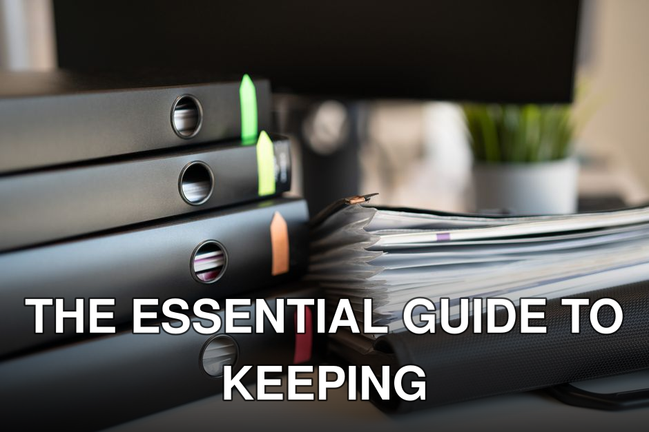 Stack of colorful ring binders and documents on a modern office desk setting.