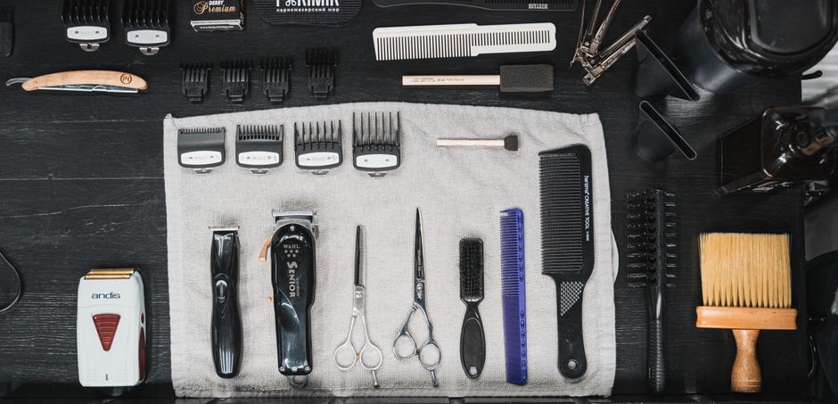 Professional hairdressing tools meticulously arranged in a flat lay, showcasing combs, clippers, scissors, and more.