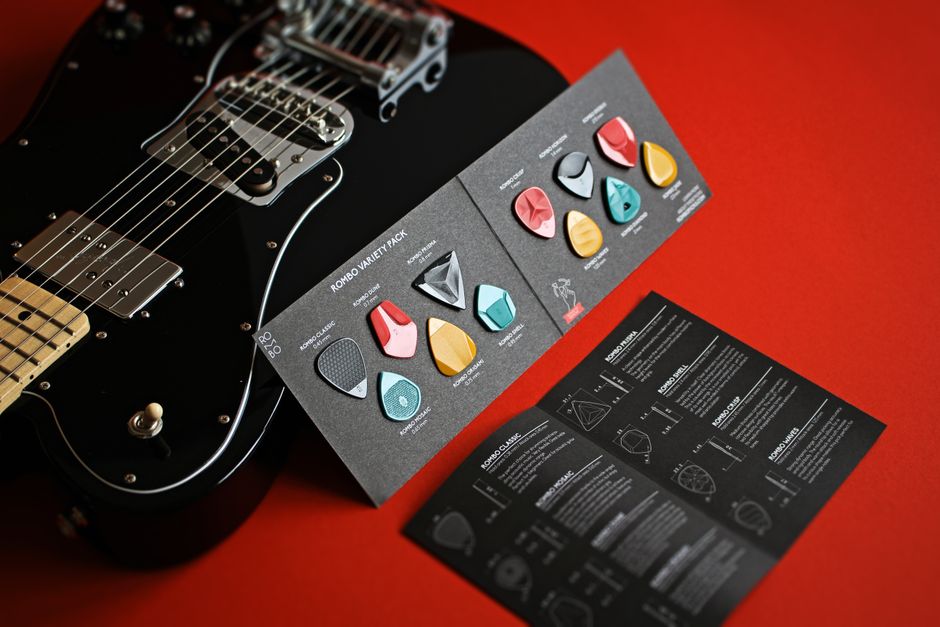 Close-up of an electric guitar with a variety of guitar picks on a red background. Ideal for music themes.