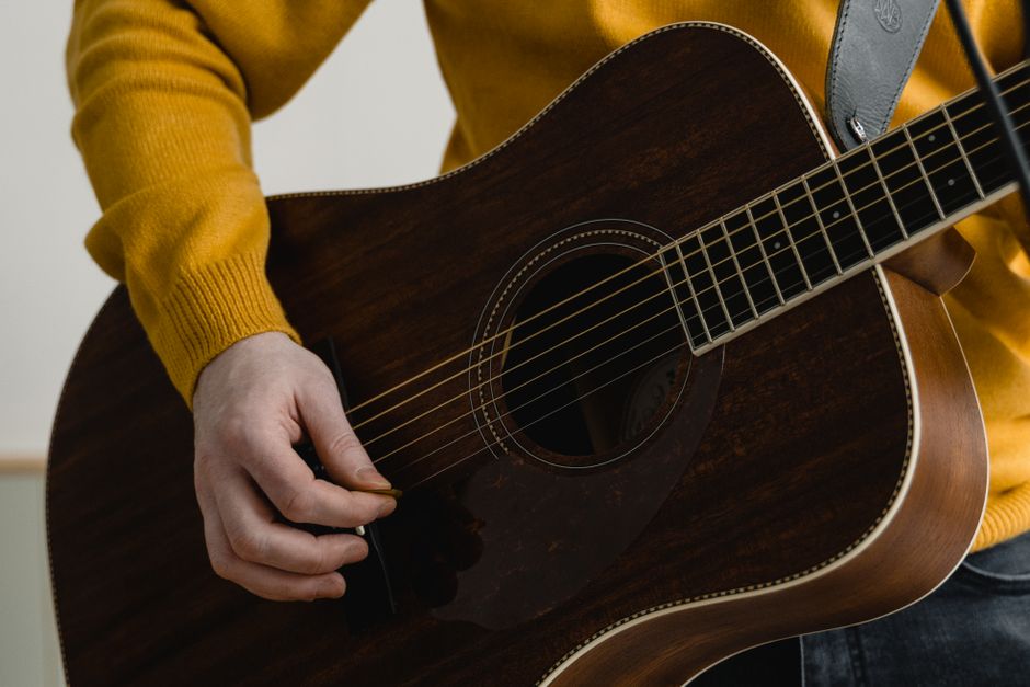 Detailed view of a hand playing an acoustic guitar. Musical expression captured.