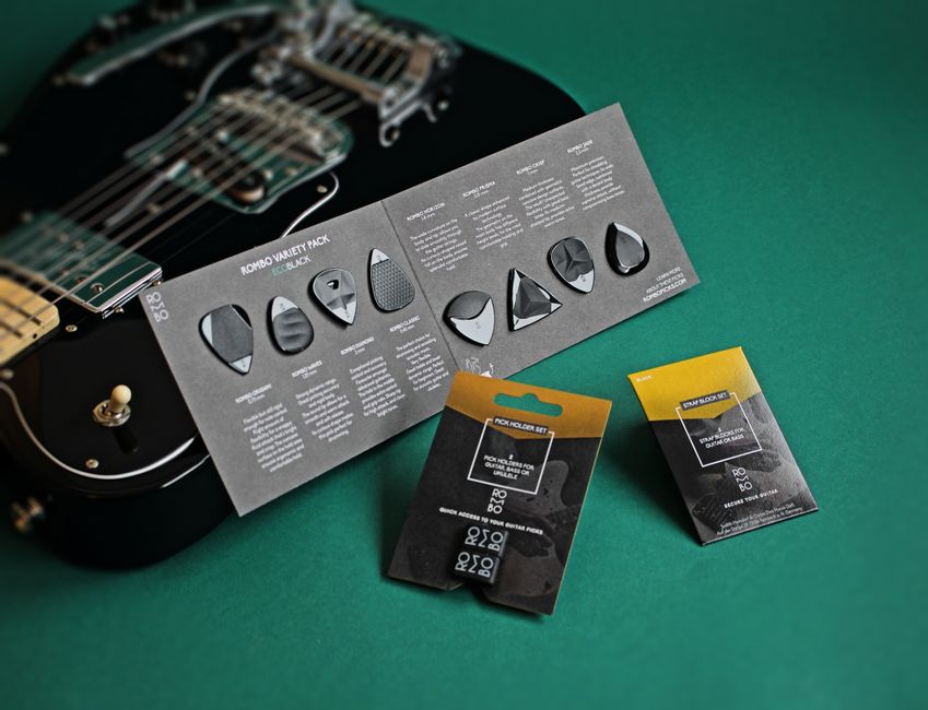 Close-up of an electric guitar with a variety of guitar picks on a green surface, highlighting musical accessories.