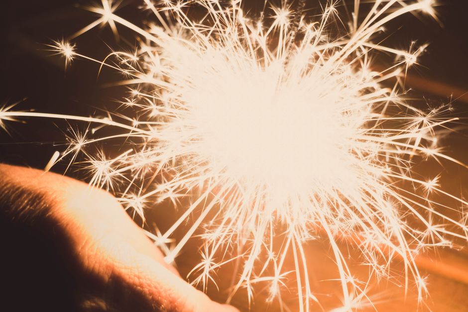 A captivating close-up image of a bright sparkler emitting dazzling sparks against a warm background.