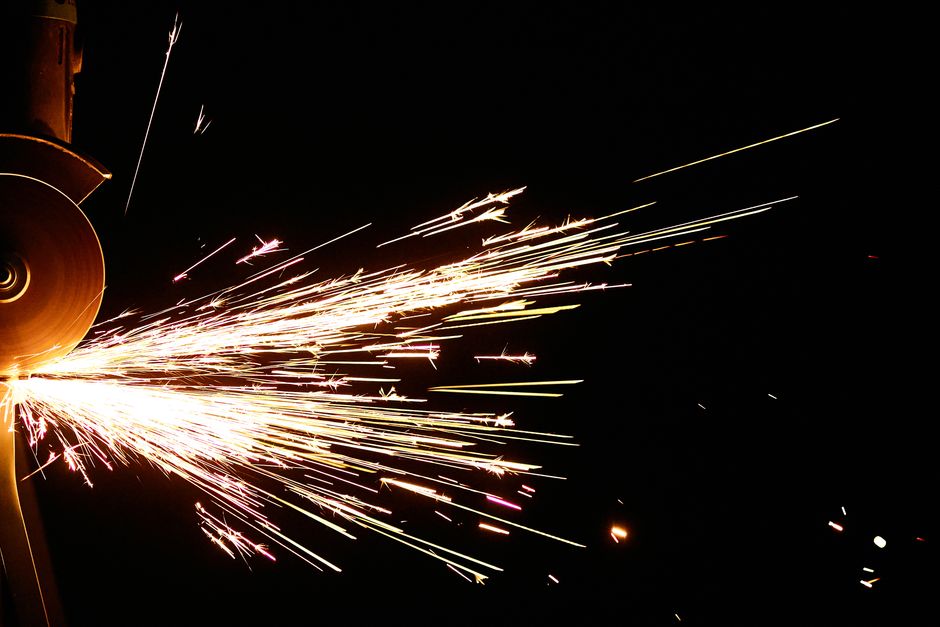 A close-up shot capturing dazzling sparks flying from an angle grinder against a black background.