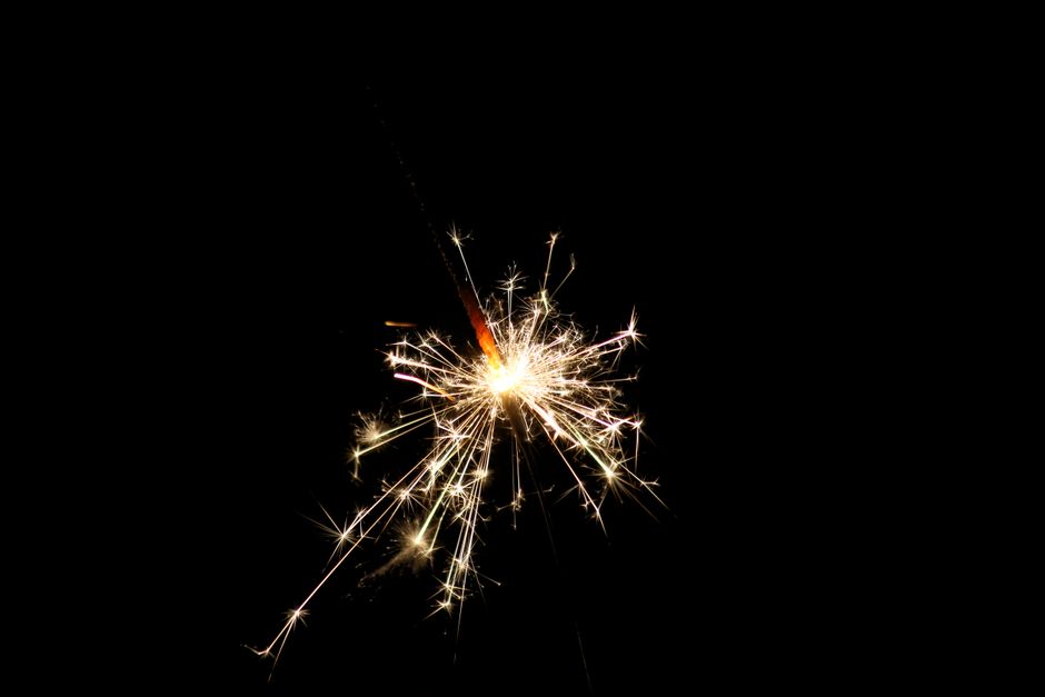 A sparkling sparkler illuminates the dark background, capturing a festive moment.